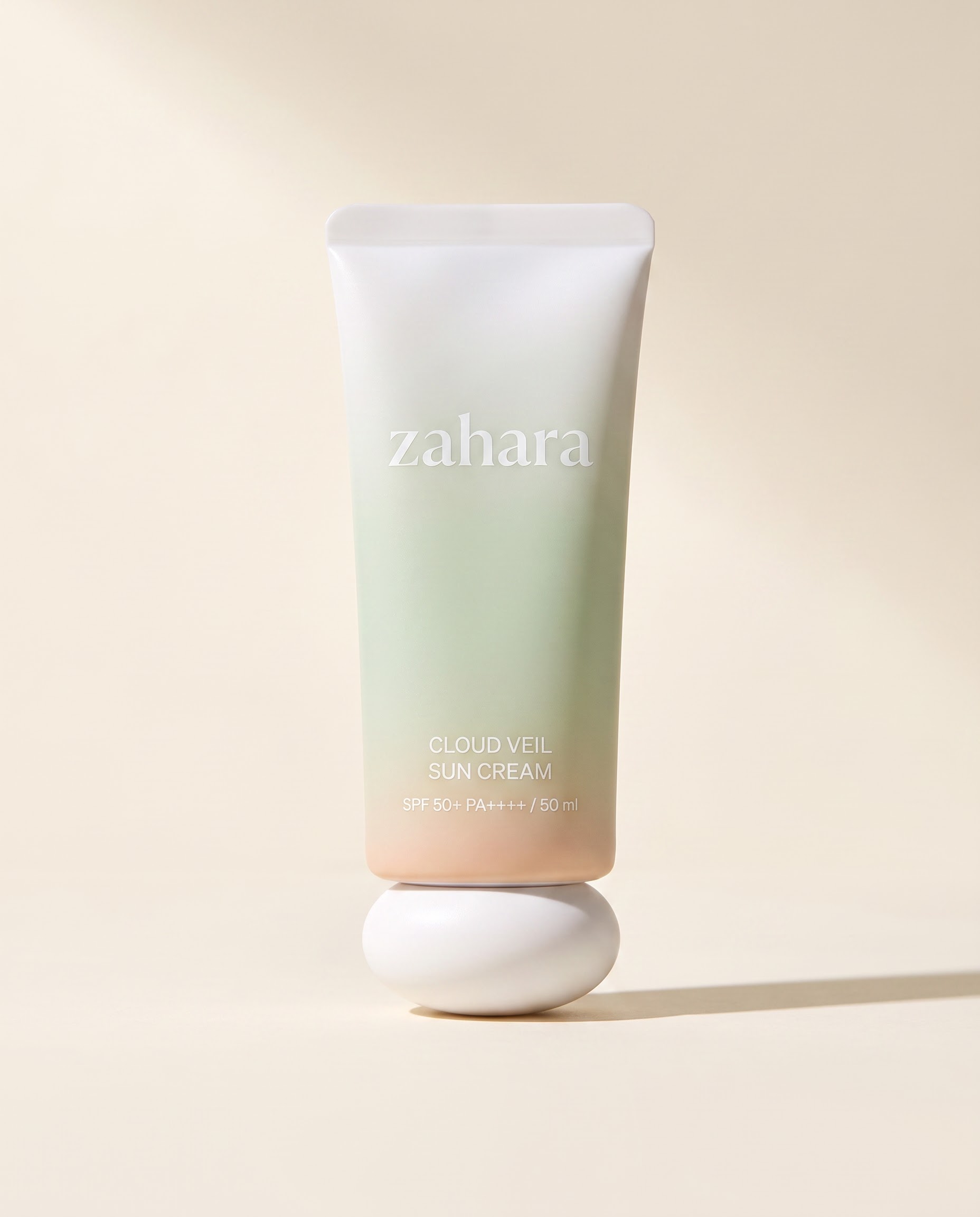 Zahara Cloud Veil Sun Cream in a porcelain-to-pale-celadon tube with a sculptural white cap.